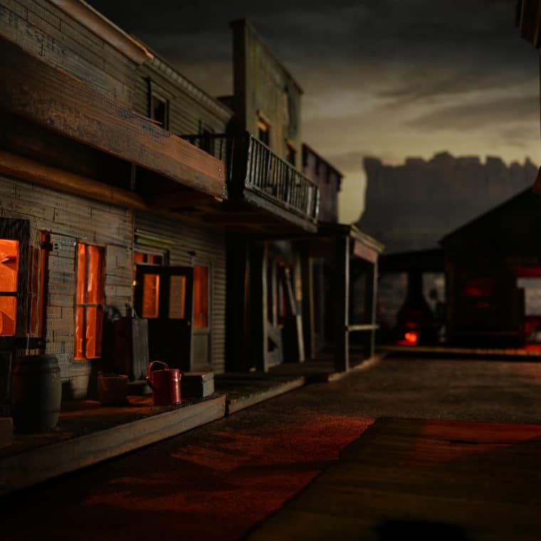 An eerie view of Buzzard Creek Ghopst town in dim light with interior lanterns glowing into the night.