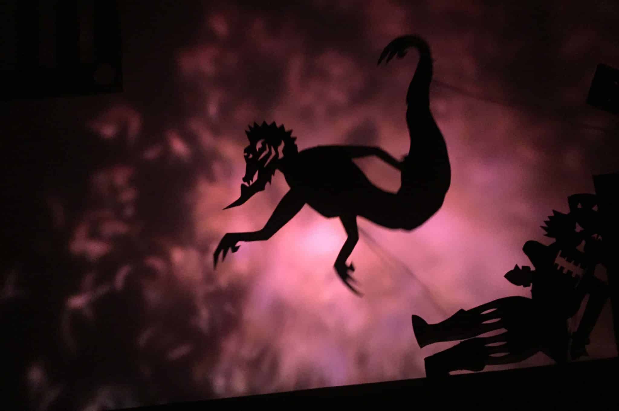 A mischevious shadow puppet character in front of an abstract background