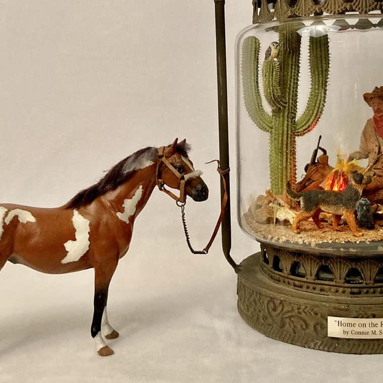 Home on the Range by Connie Sauve - cowboy and campfire inside a lantern with a model horse outside the lantern.
