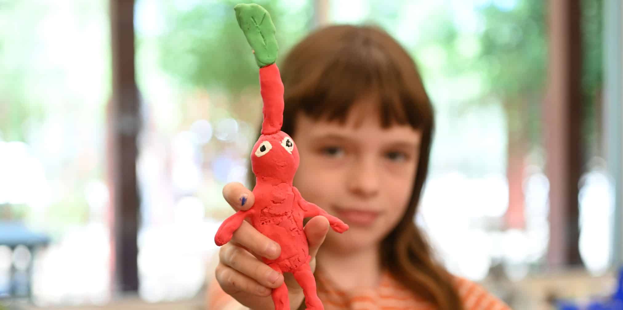 Girl holding up artwork created in The Mini TIme Machine Museum of Miniatures Summer Camp
